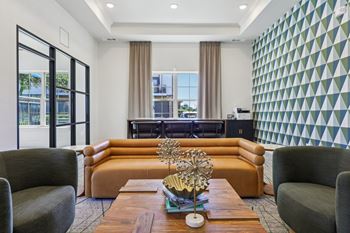 A living room with a brown sofa, a grey armchair, and a wooden coffee table with a gold sculpture on it.